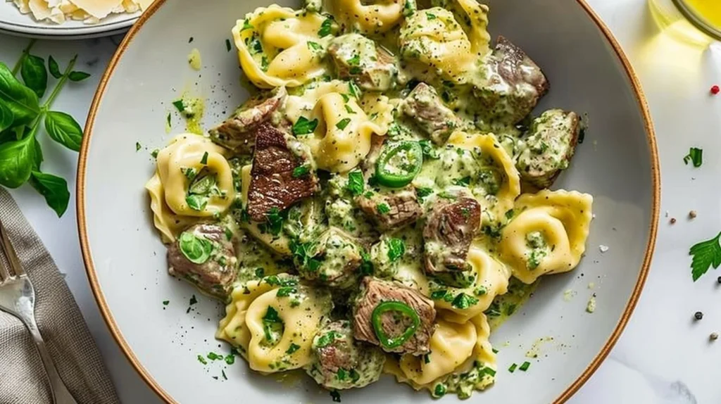 A delicious bowl of Garlic Steak Tortellini with Pesto Cream, garnished with herbs.