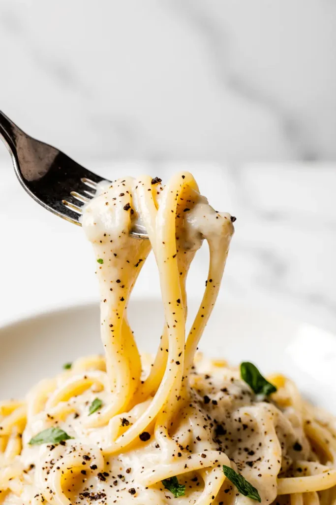 A pot filled with creamy white pasta shells, garnished with fresh parsley and grated parmesan cheese. Easy one pot dinner recipe.