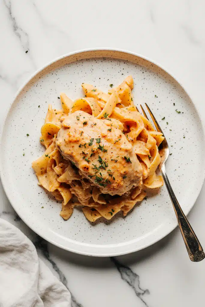Skillet filled with golden chicken breasts in a creamy orange sauce with sun-dried tomatoes and basil leaves. Marry Me Chicken recipe.